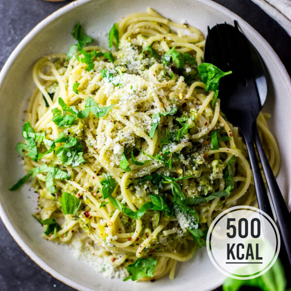 Nudeln mit geriebener Zucchini, Zitronensauce und Parmesan, garniert mit Basilikum - kalorienarmes Rezept für den Sommer. Die Zucchini wird in einer Pfanne mit Zwiebel und Knoblauch gebraten und bekommt durch Zitrone und Parmesan einen tollen Geschmack. Das Gericht ist in ca. 20 Minuten fertig. - kaloriengeniessen.de #abendessen #dinner #kalorienarm #zucchini #500kalorien #sauce #zitrone #gemüse