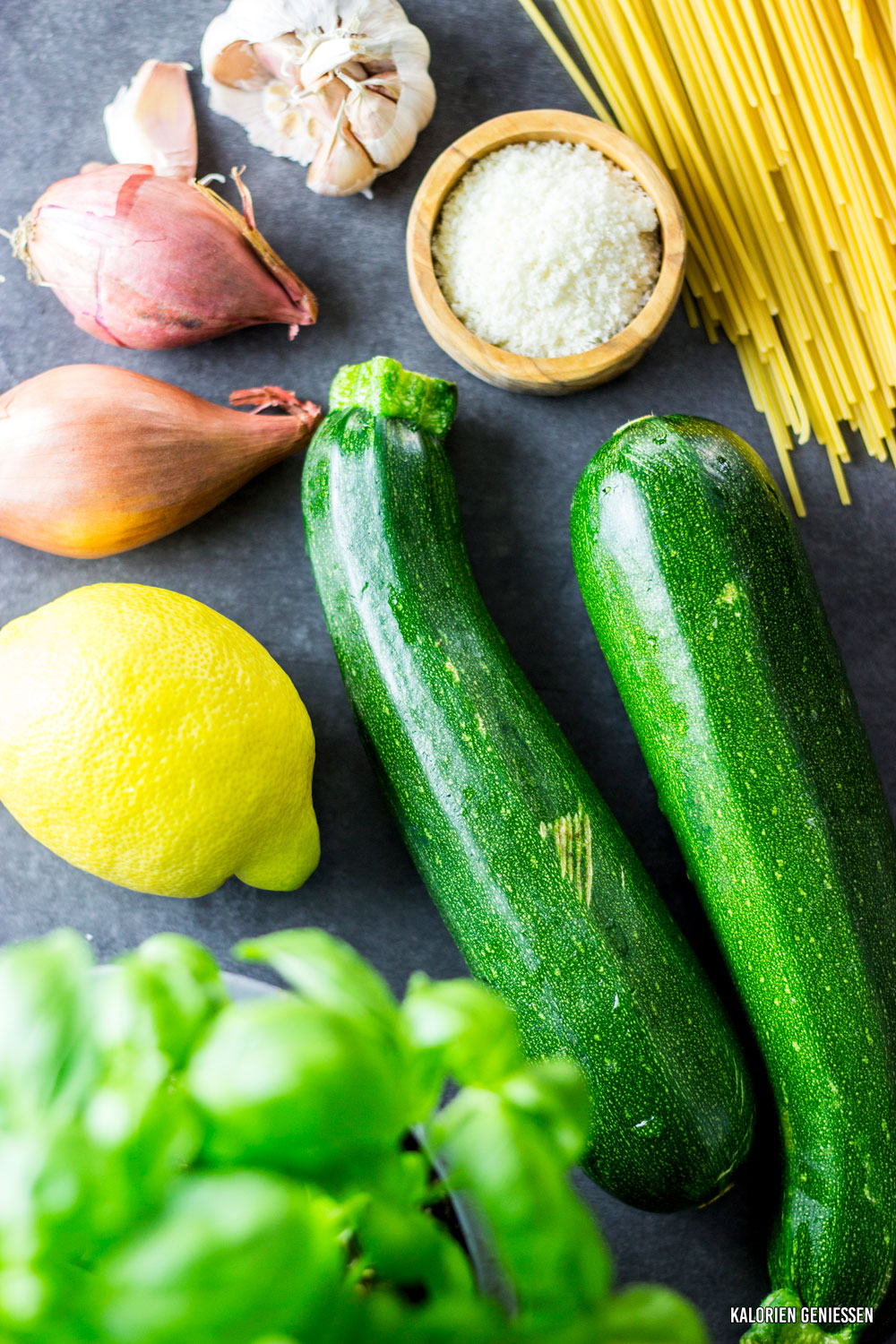 Nudeln mit geriebener Zucchini, Zitronensauce und Parmesan, garniert mit Basilikum - kalorienarmes Rezept für den Sommer. Die Zucchini wird in einer Pfanne mit Zwiebel und Knoblauch gebraten und bekommt durch Zitrone und Parmesan einen tollen Geschmack. Das Gericht ist in ca. 20 Minuten fertig. - kaloriengeniessen.de #abendessen #dinner #kalorienarm #zucchini #500kalorien #sauce #zitrone #gemüse