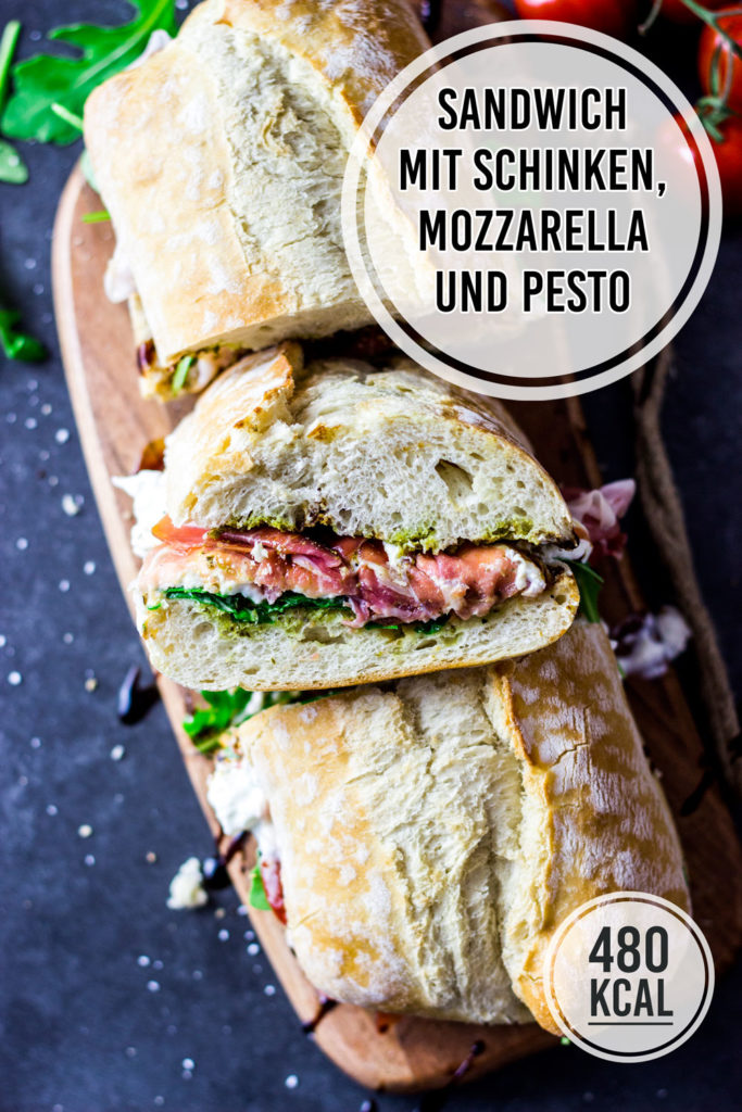 Saftiges Sandwich-Baguette mit Pesto, Rucola, Mozzarella / Burrata, Tomaten und Schinken. Kalorienarmes und sättigendes Sandwich zum Mittagessen. Ein belegtes Sandwich hat 480 Kalorien. Einfaches und kalorienarmes Rezept. Gesundes und kalorienarmes Kochen. Einfache Rezepte zum Abnehmen. - kaloriengeniessen.de #sandwich #ciabatta #baguette #panini #brot #kaloriengeniessen #rezeptezumabnehmen #burrata #mozzarella 